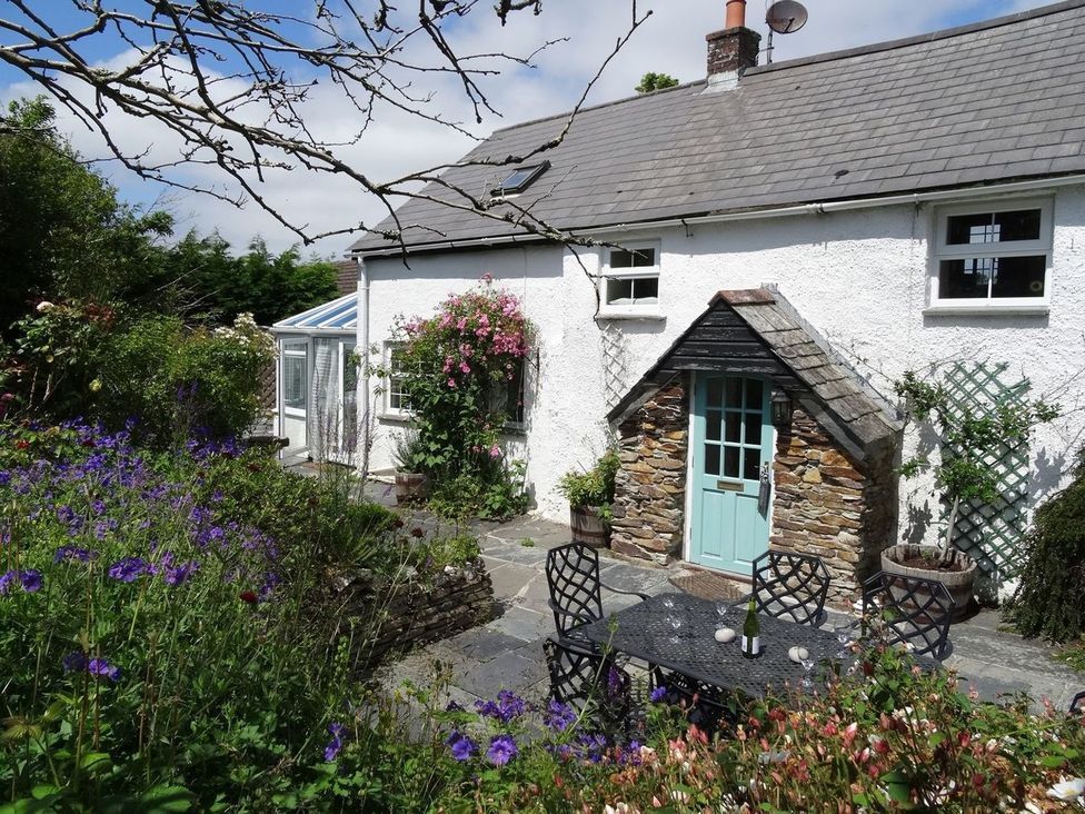 A cottage with a garden and a dining table at Mays Cottage in Wadebridge