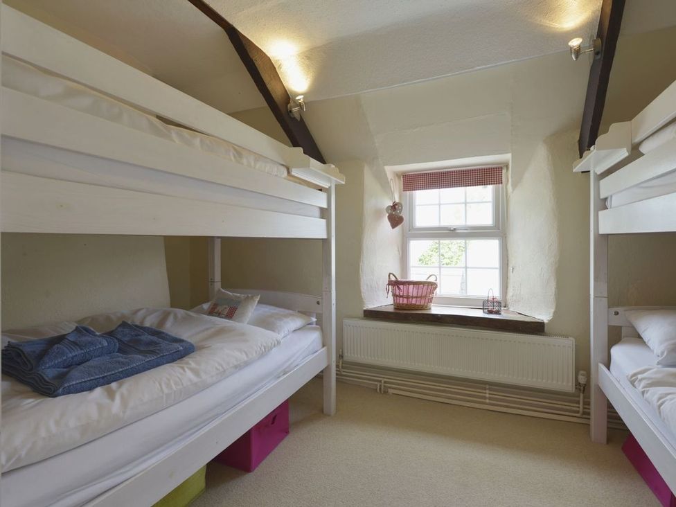A bedroom with bunk beds and a window at Mays Cottage in Wadebridge