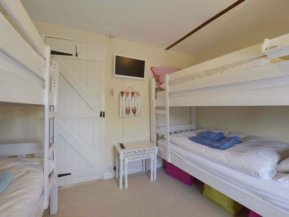 A bedroom with bunk beds and a television at Mays Cottage in Wadebridge