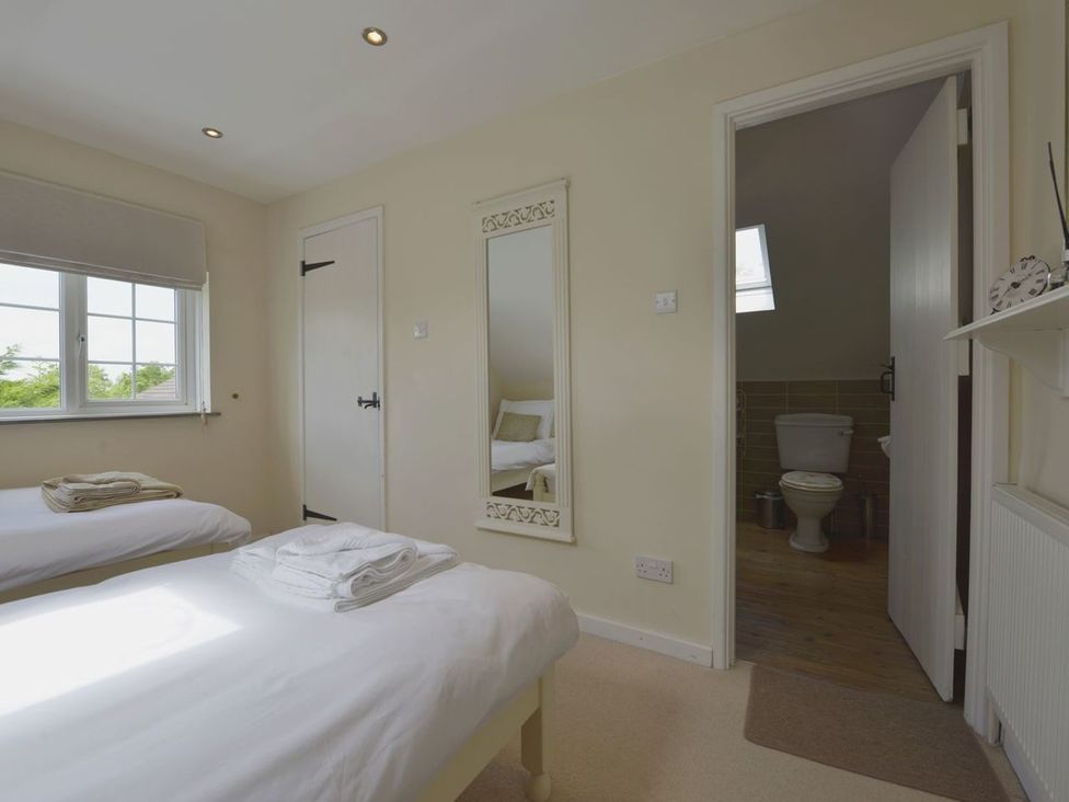 A bedroom with two beds and a mirror at Mays Cottage in Wadebridge