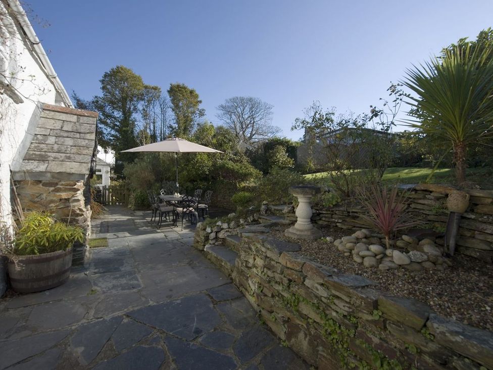 A garden with a table and chairs under an umbrella at Mays Cottage in Wadebridge