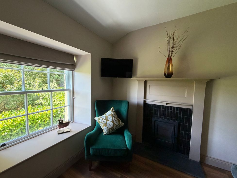 A snug with a green chair and a television at Kirkstone Brow in Ambleside