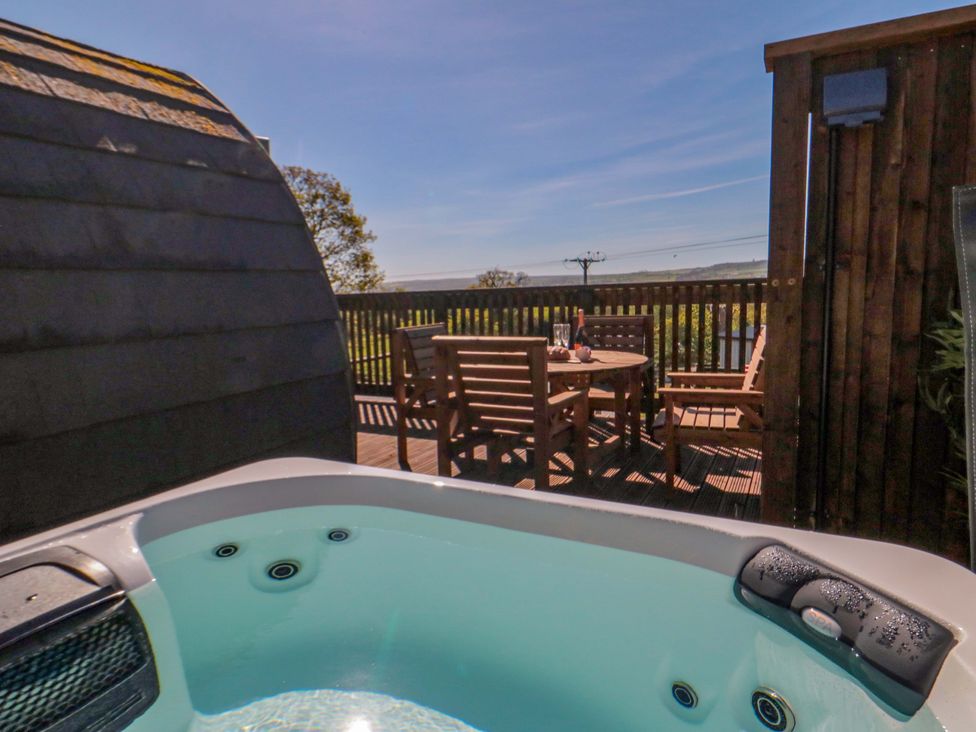 A hot tub and a wooden table with chairs at Heather Heights in Whitby