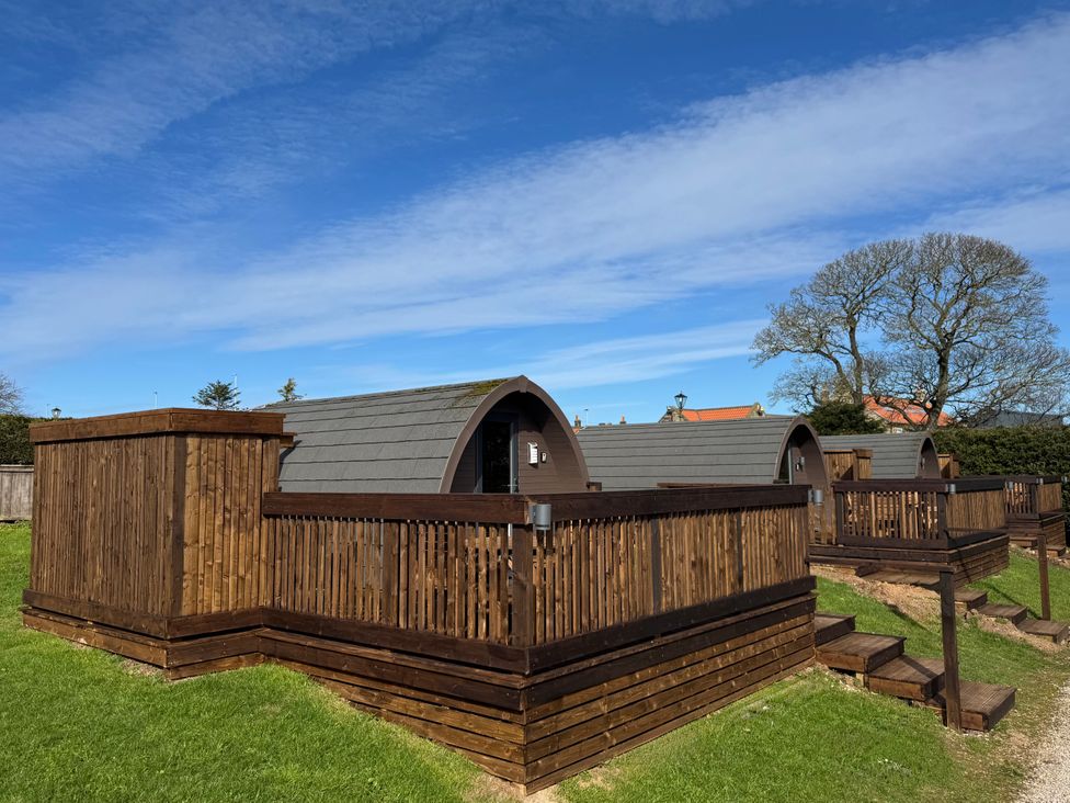 Wooden cabins with balconies and steps in a grassy area at Rosemary Retreat in Whitby