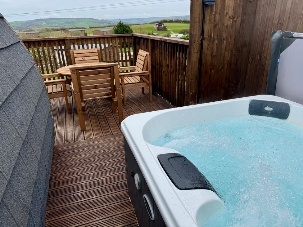 A hot tub and wooden furniture on a deck at Rosemary Retreat in Whitby
