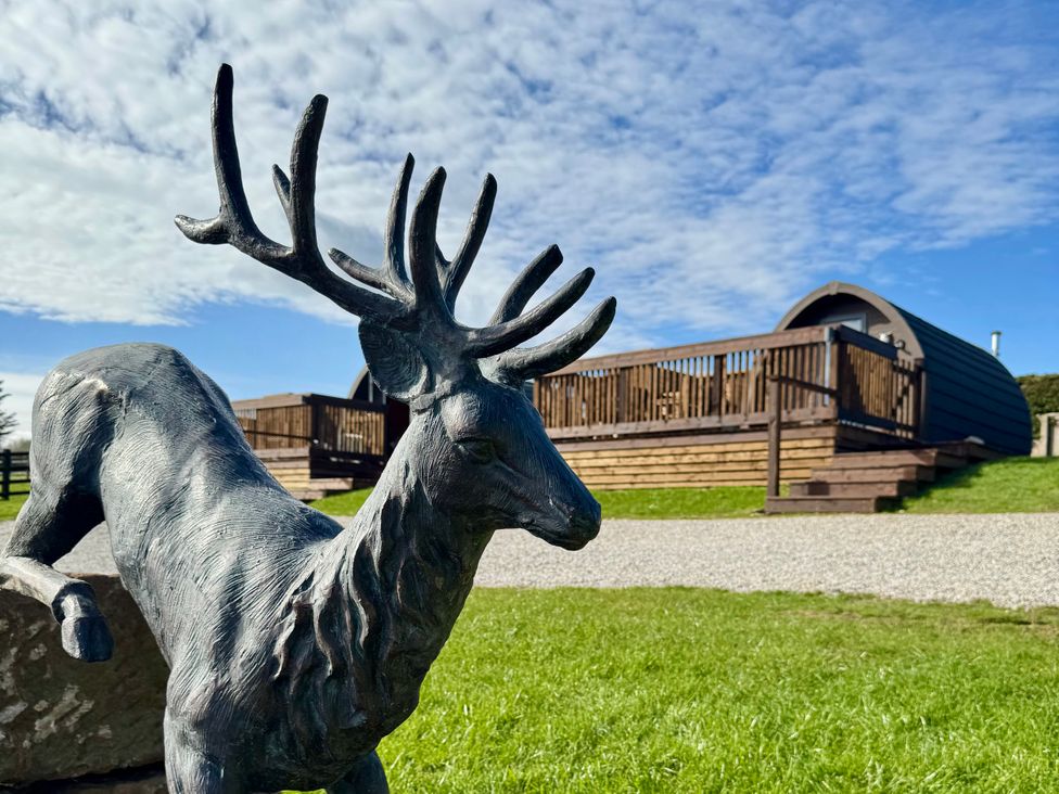A deer statue with a wooden cabin in the background at Rosemary Retreat in Whitby