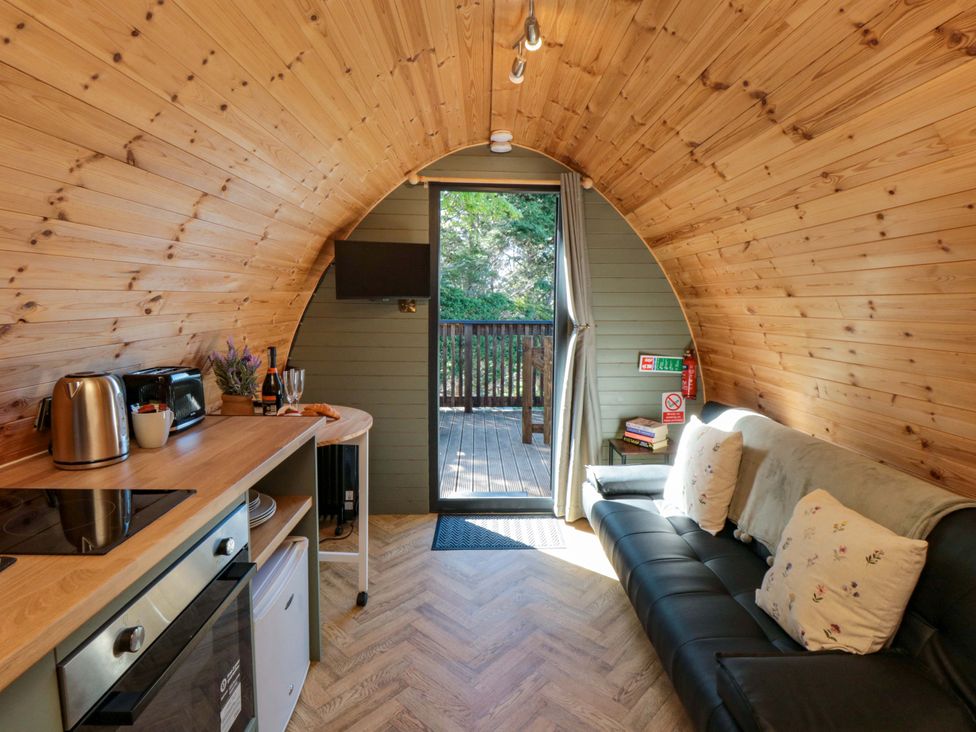 A living room with a kitchenette, sofa, and door to a deck at Sage Sanctuary in Whitby