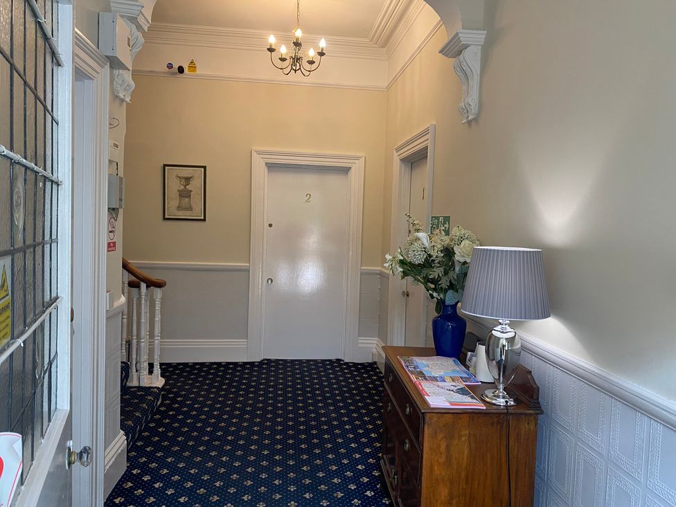 A hallway with a lamp and flowers on a table at Apartment 2 in Torquay