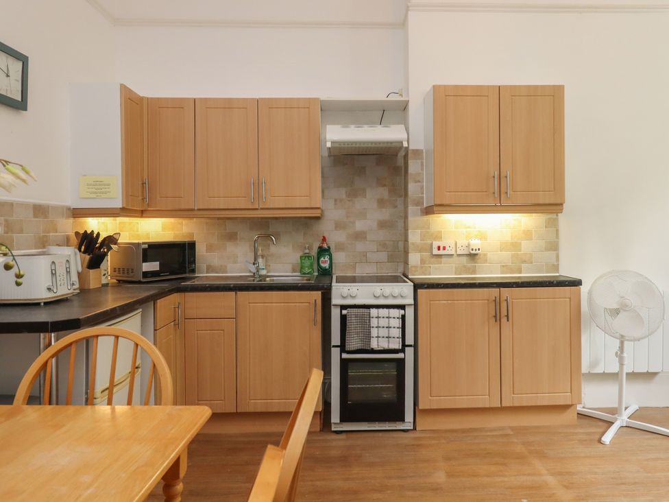A kitchen with wooden cabinets and appliances at Apartment 2 in Torquay