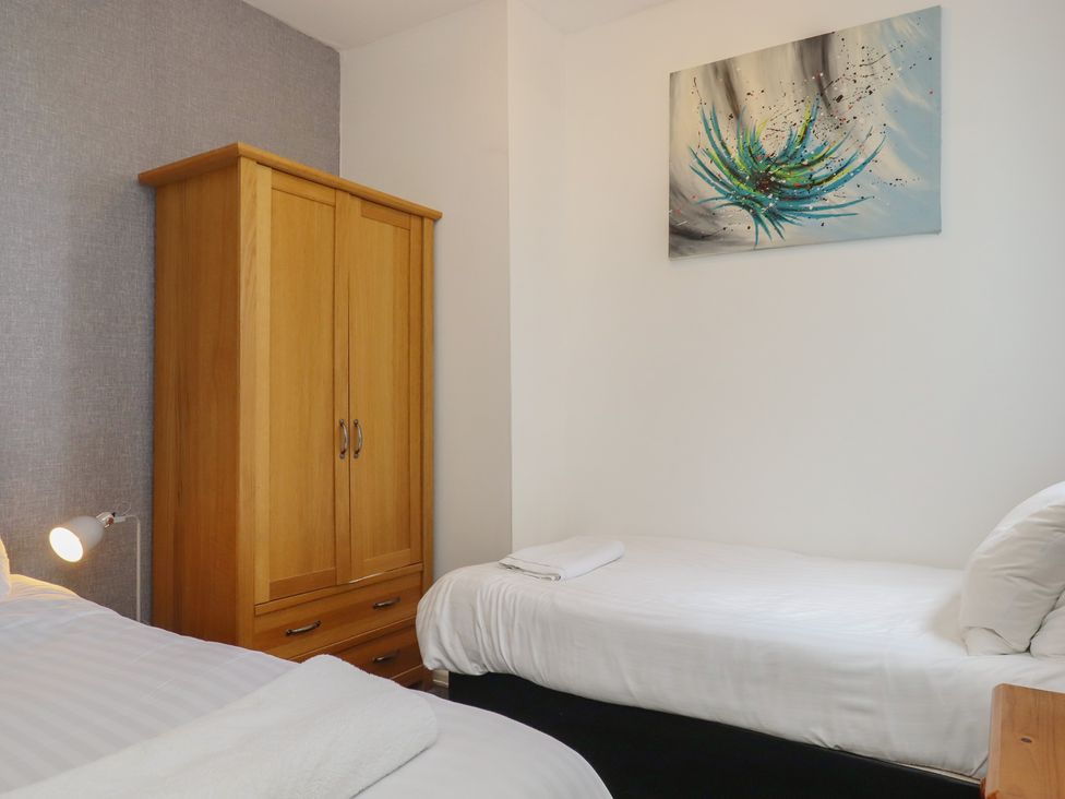 A bedroom with two beds and a wardrobe at Apartment 2 in Torquay