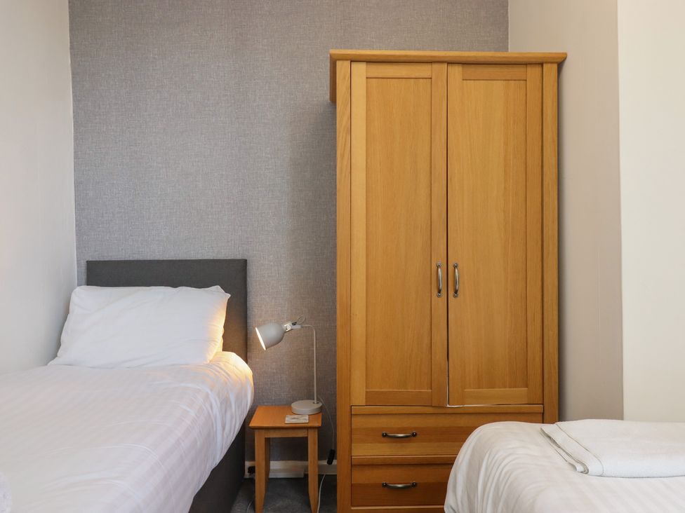 A bedroom with a single bed and a wooden wardrobe at Apartment 2 in Torquay