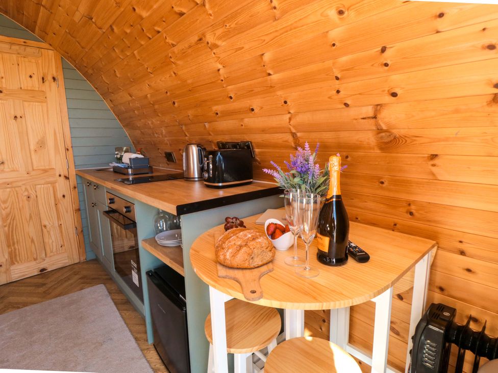A kitchen with a counter, stools, and appliances at Fern Folly in Whitby