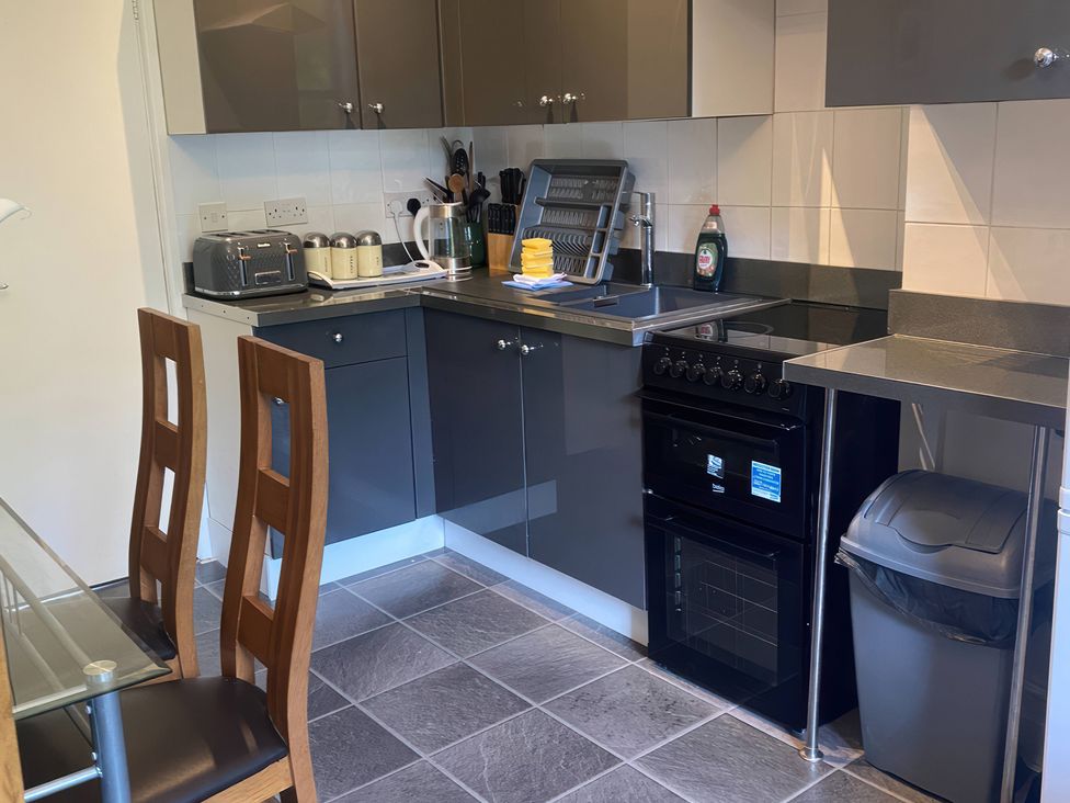 A kitchen with cabinets, stove, sink and dining table at Apartment 5 in Torquay