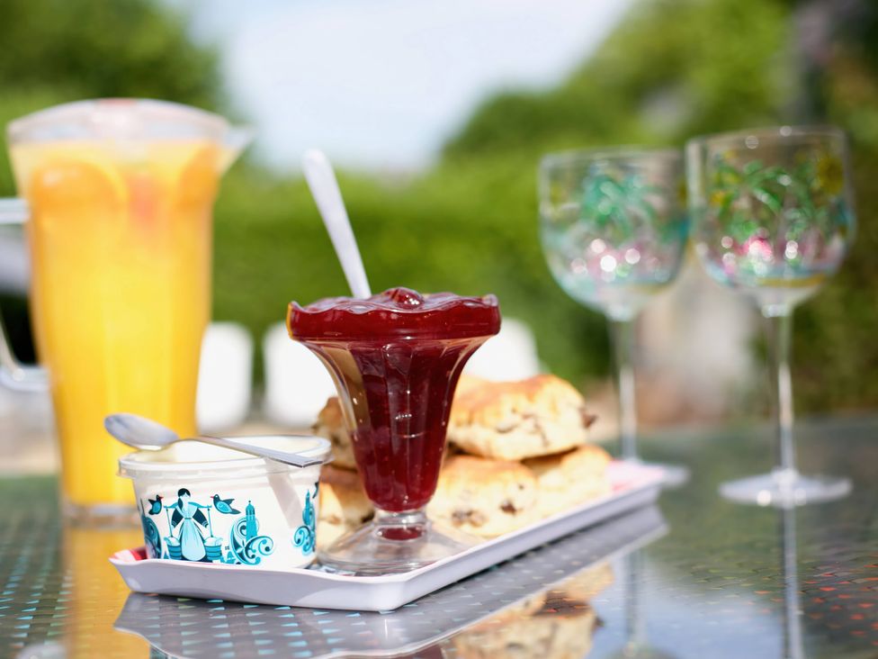 A table with scones, jam, cream, and beverages at Apartment 5 in Torquay