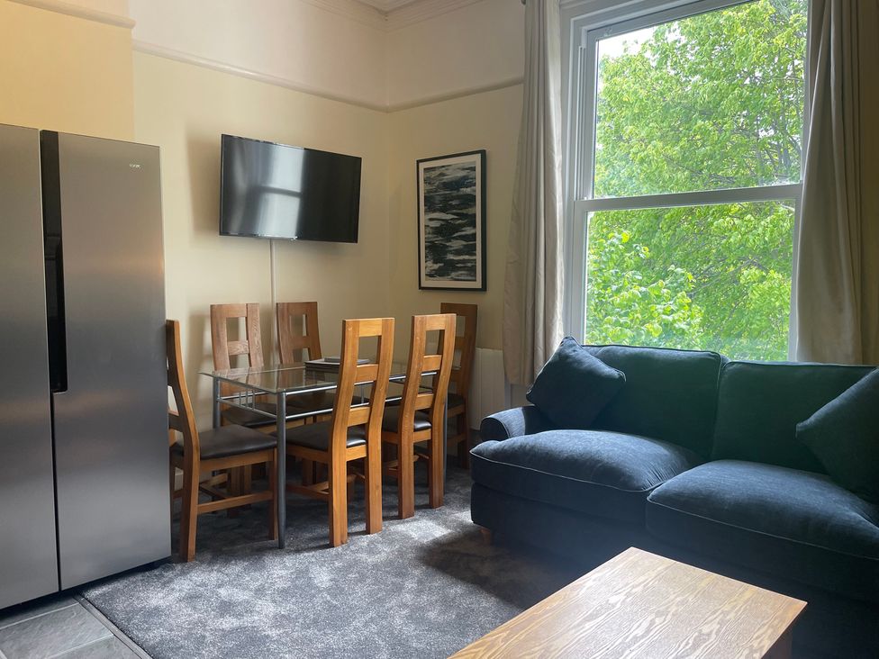 A living room with a dining table and chairs and a refrigerator at Apartment 5 in Torquay