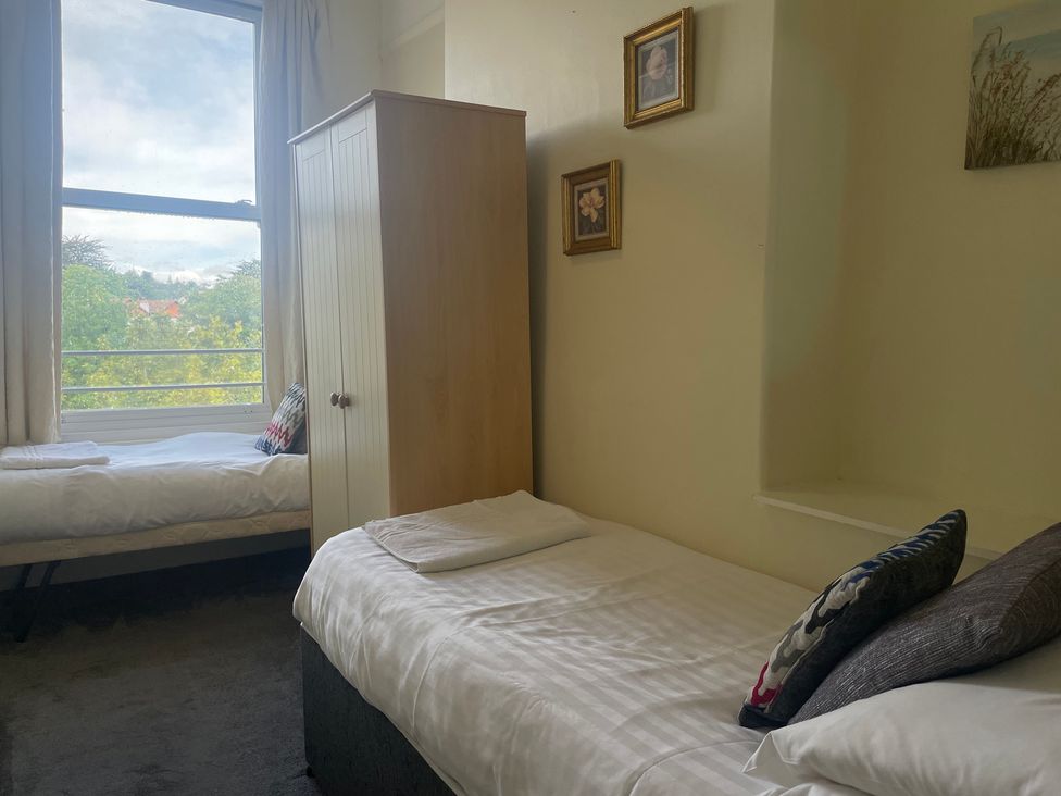 A bedroom with two beds and a wardrobe at Apartment 5 in Torquay