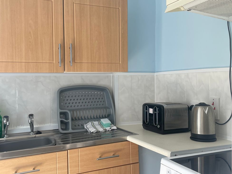 A kitchen with a sink, draining rack, toaster, and kettle at Apartment 6 in Torquay