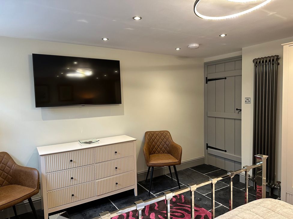 A bedroom with television and chairs at La'al Kirkstone Brow in Ambleside