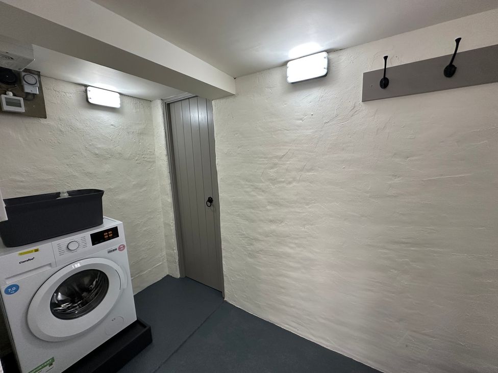 A laundry room with a washing machine and a door at La'al Kirkstone Brow in Ambleside