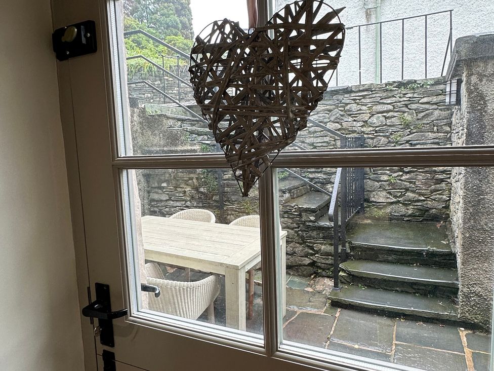 A window with a heart decoration looking out to an outdoor patio at La'al Kirkstone Brow in Ambleside