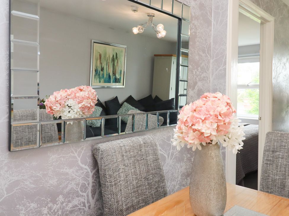 A dining room with a mirror and floral arrangement at Apartment 10 in Torquay