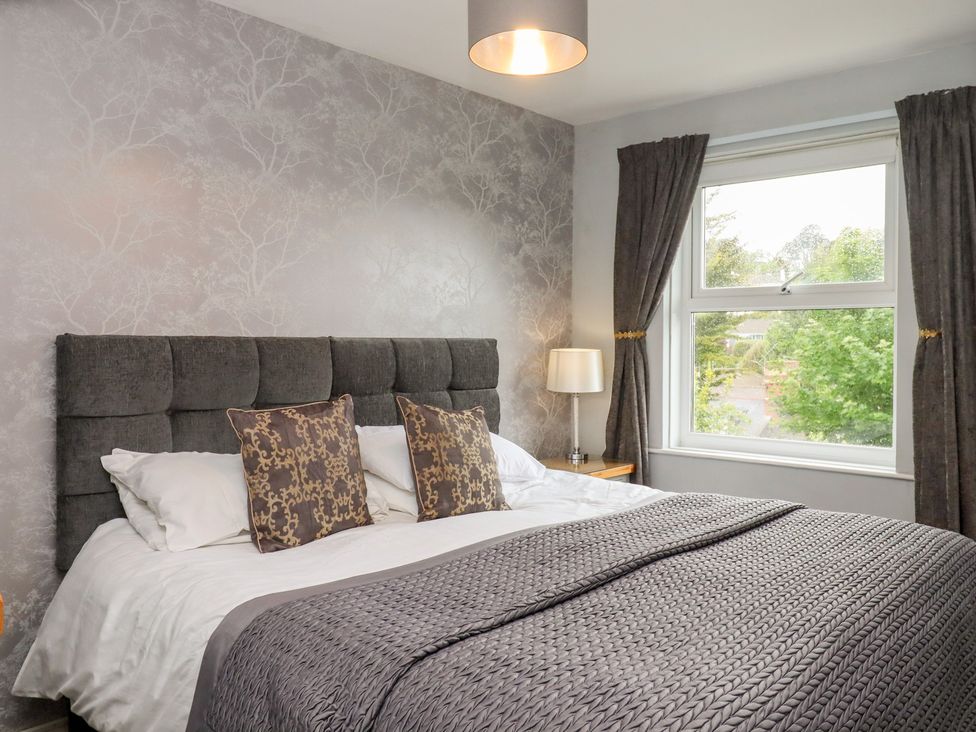 A bedroom with a bed, bedside lamp and window at Apartment 10 in Torquay