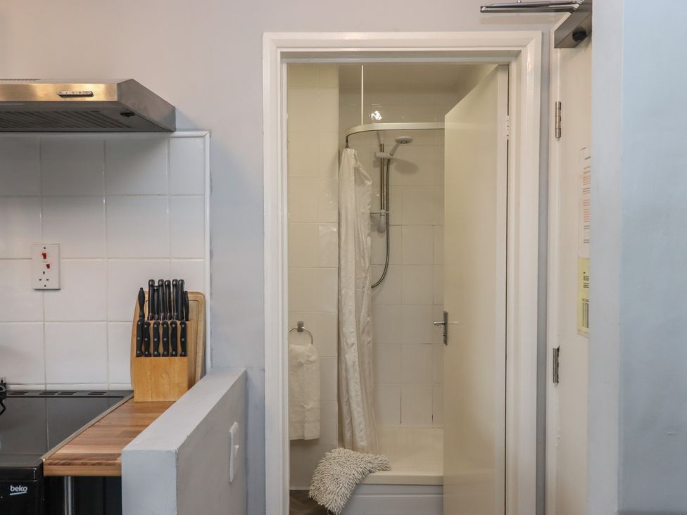 A kitchen with a stove and a shower area at Apartment 10 in Torquay