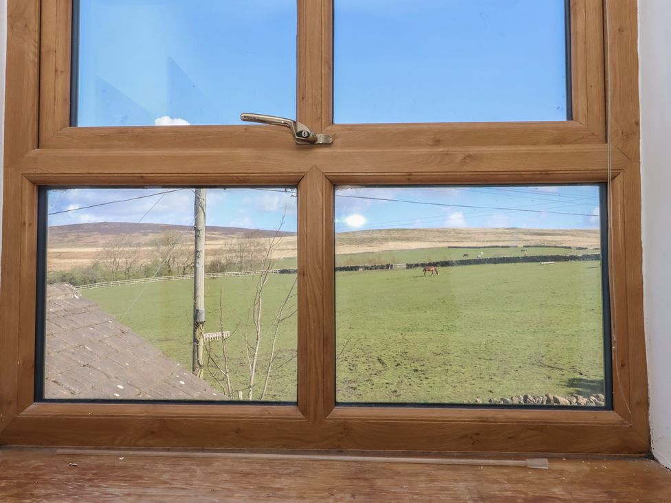 A view of a landscape with horses through a window at 1 Upper Austby Farm Cottage Ilkley
