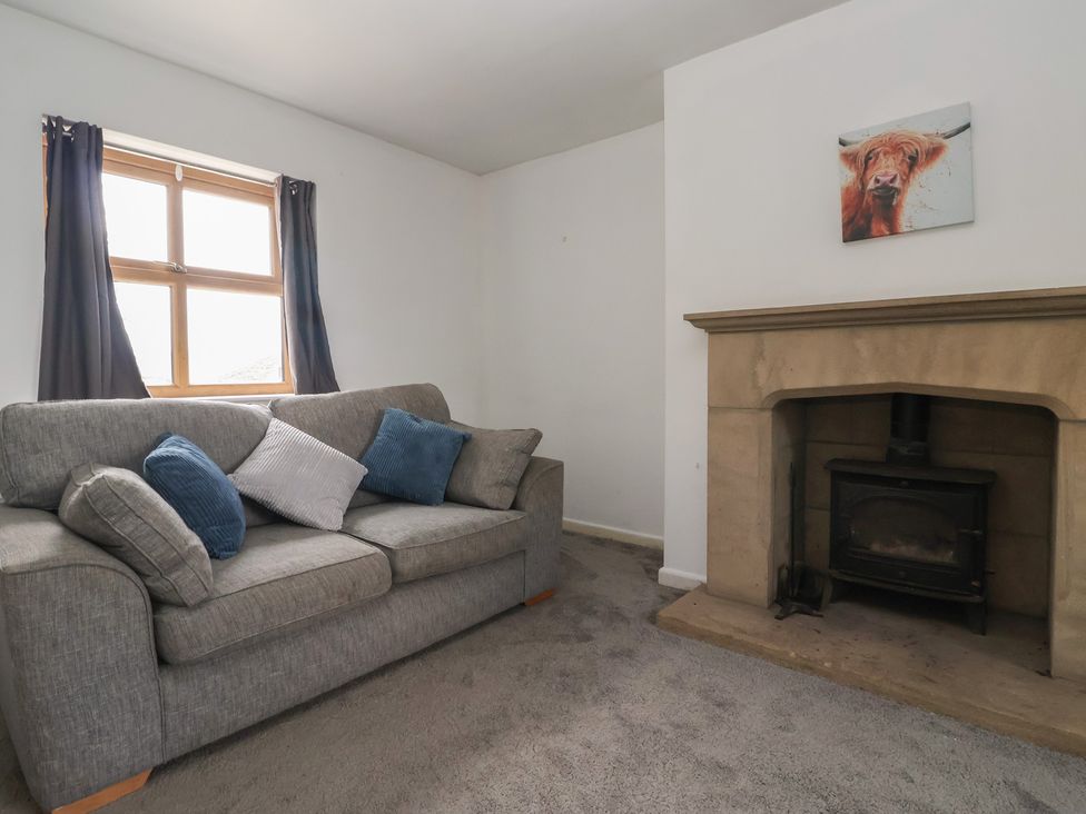 A living room with a grey sofa and fireplace at 1 Upper Austby Farm Cottage in Langbar near Ilkley