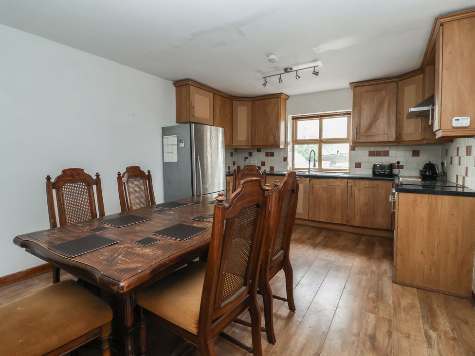 A kitchen with a dining table and refrigerator at 1 Upper Austby Farm Cottage in Langbar near Ilkley