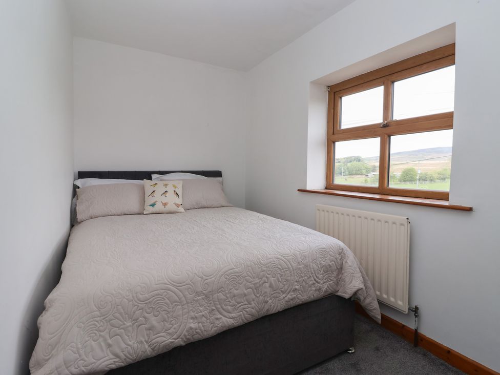 A bedroom with a bed and window at 1 Upper Austby Farm Cottage Langbar near Ilkley