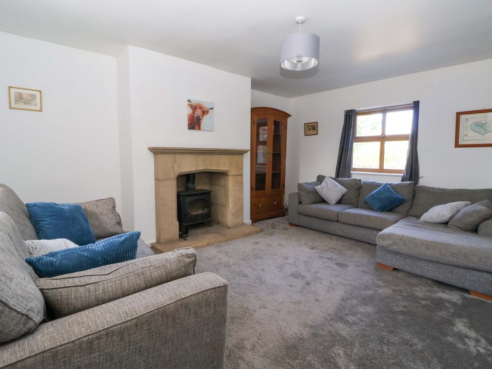 A living room with sofas, a fireplace and a cabinet at 1 Upper Austby Farm Cottage in Langbar near Ilkley