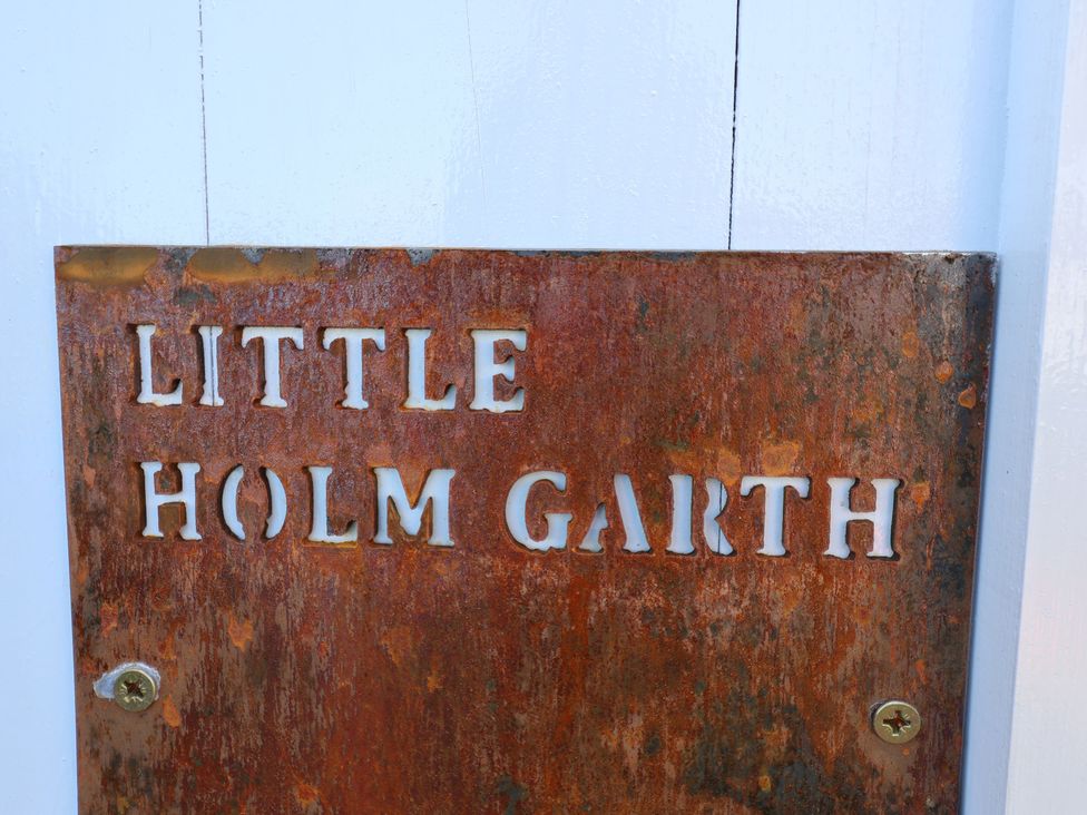 A rusted metal sign with the text Little Holm Garth