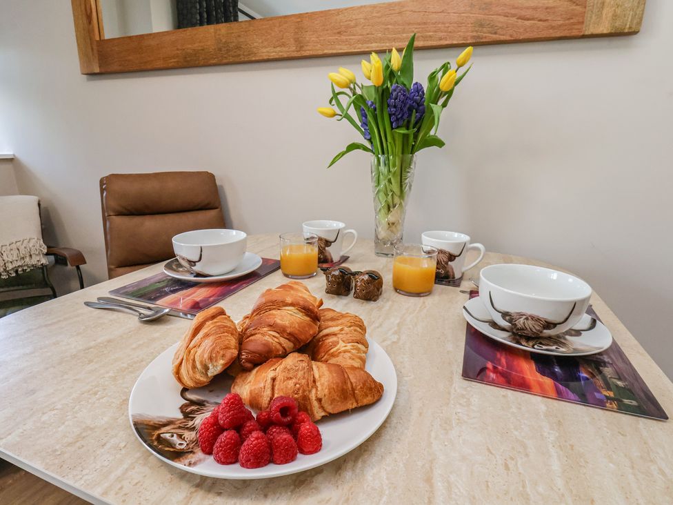 A dining room with croissants and raspberries on a table at Little Holm Garth