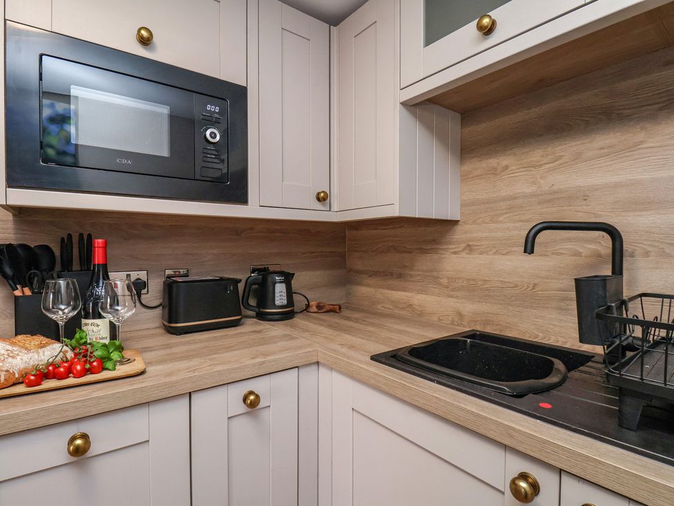 A kitchen with a microwave, sink, and kitchen appliances at Little Holm Garth