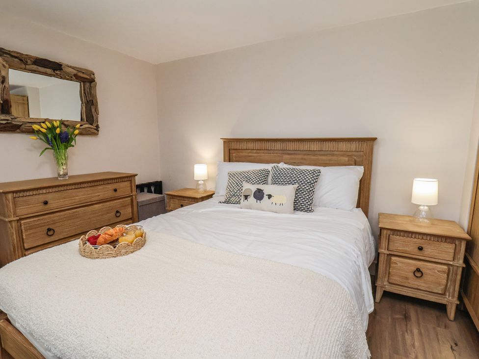 A bedroom with a bed and wooden furniture at Little Holm Garth 
