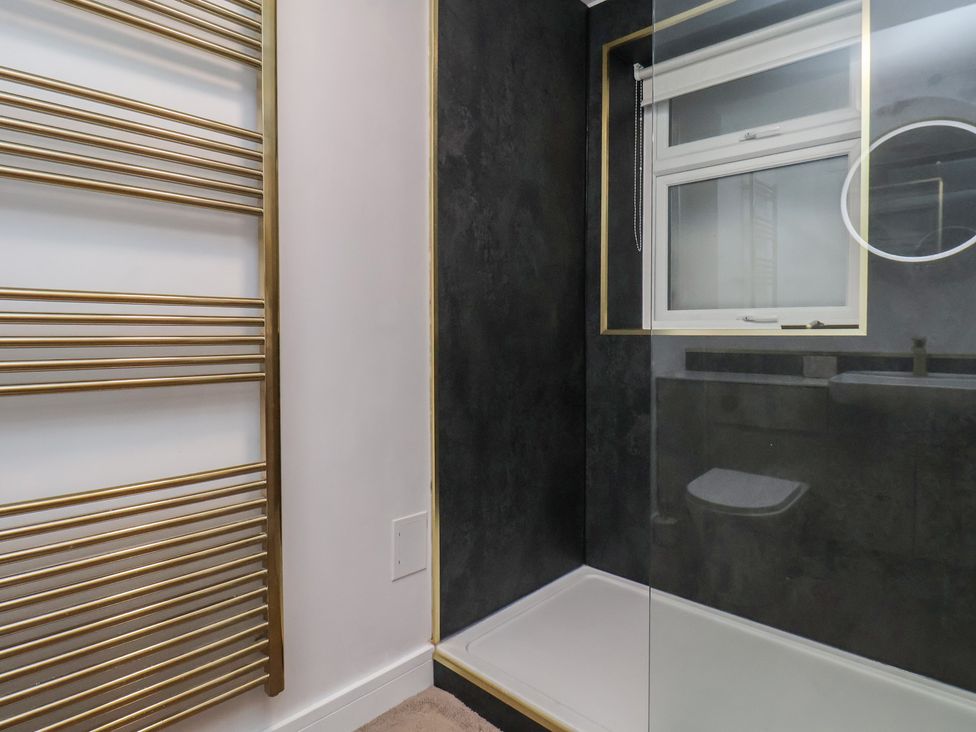 A bathroom featuring a shower, window, towel rack, and toilet at Little Holm Garth