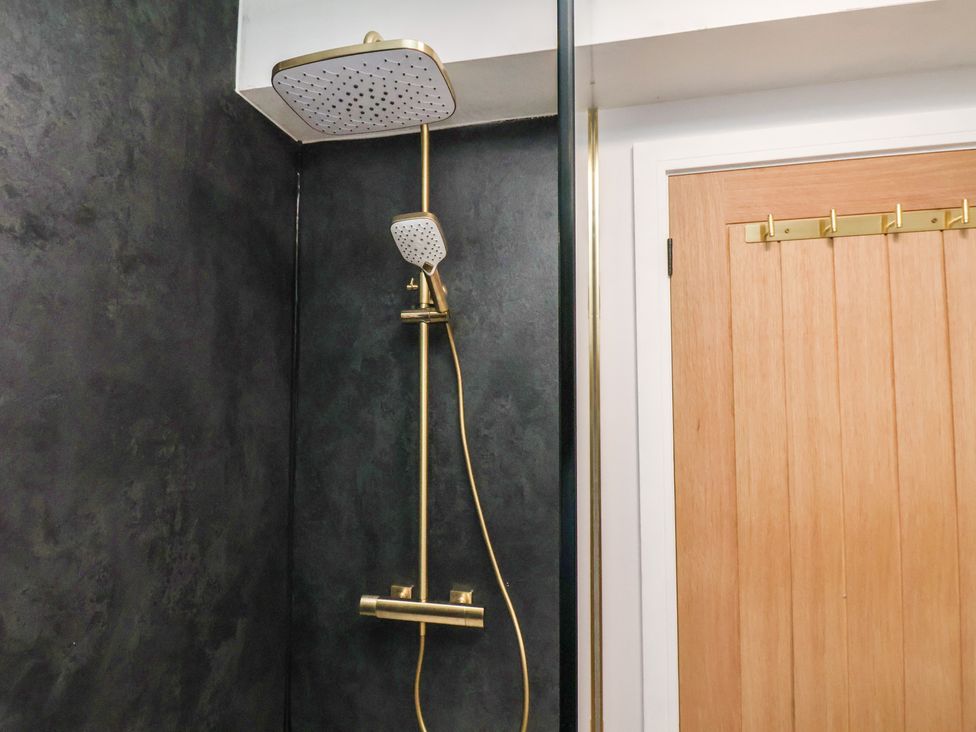 A shower with a gold shower head and control at Little Holm Garth