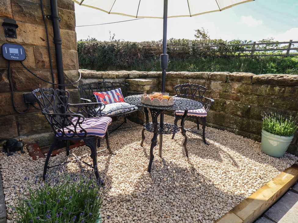 An outdoor seating area with a table and chairs under an umbrella at Little Holm Garth
