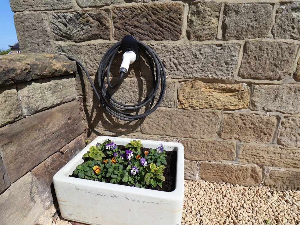 A flower pot with colorful flowers near a wall at Little Holm Garth