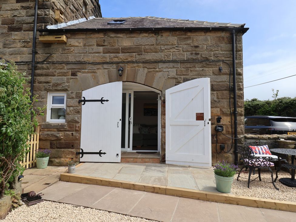 An outdoor area with stone wall and double doors at Little Holm Garth in Whitby