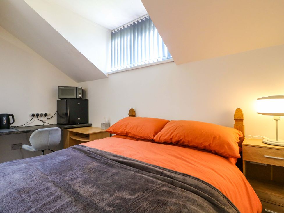 A bedroom with a bed, desk, and kitchenette at 57 Abbey Street