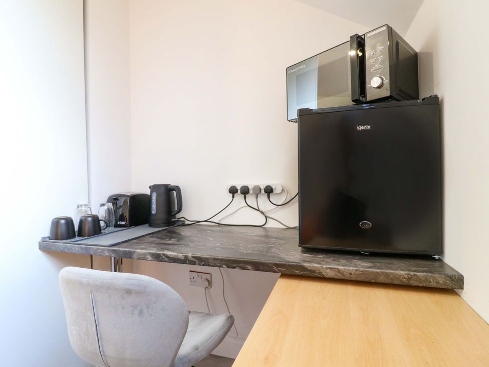 A kitchenette with a microwave, mini fridge, and kettle at 57 Abbey Street