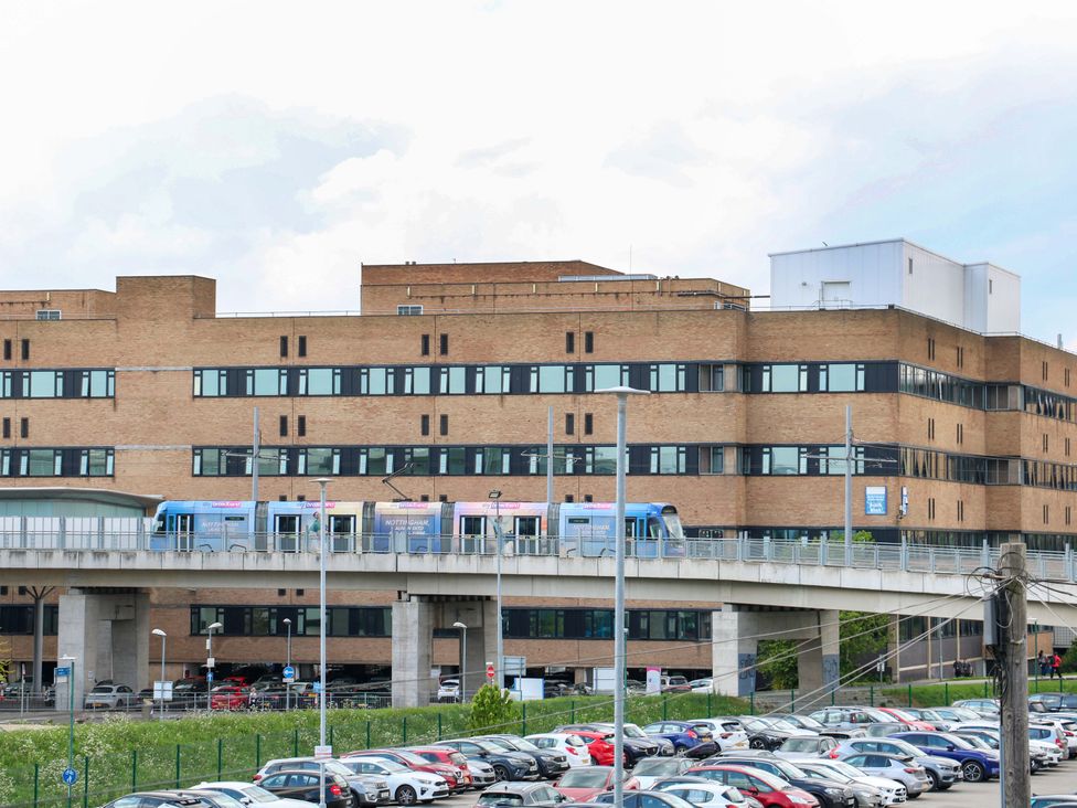 A building with a train on an elevated track and cars in a parking lot at 57 Abbey Street