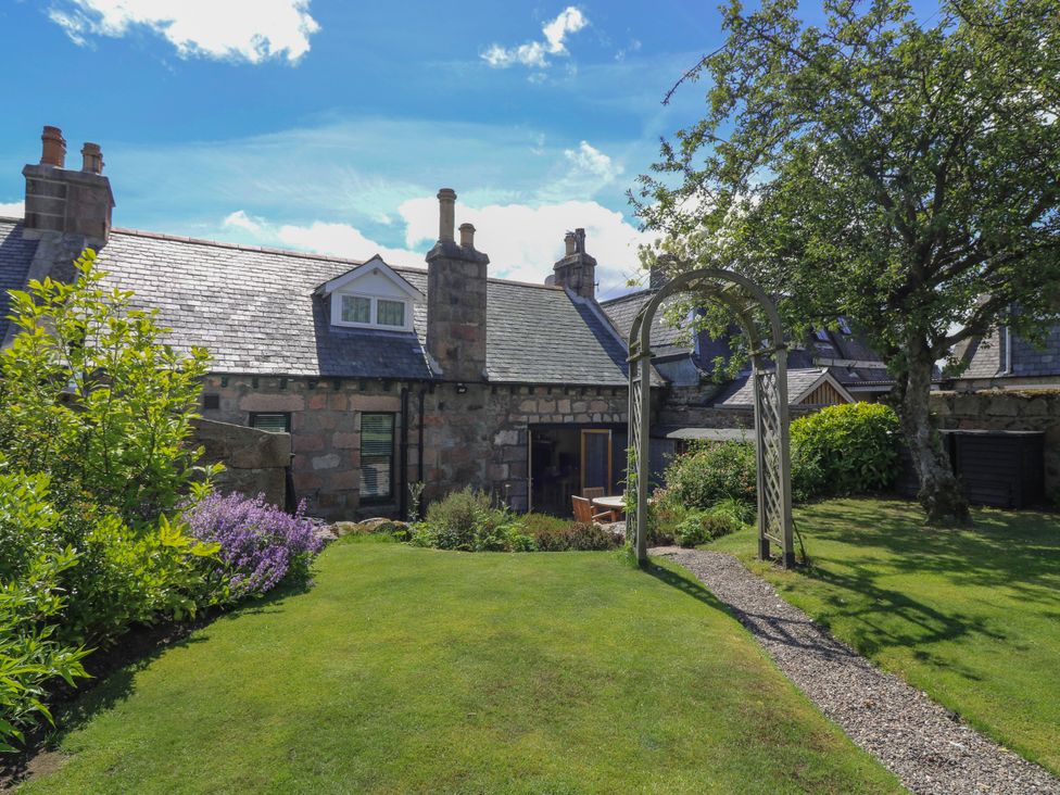 A garden with a house and archway at St Kilda in Ballater
