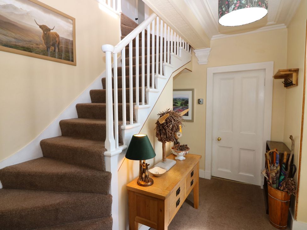 A hallway with a staircase and a table at St Kilda in Ballater