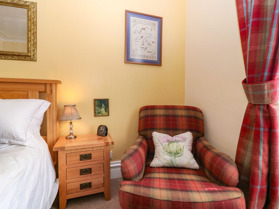 A bedroom with a bed and an armchair at St Kilda in Ballater
