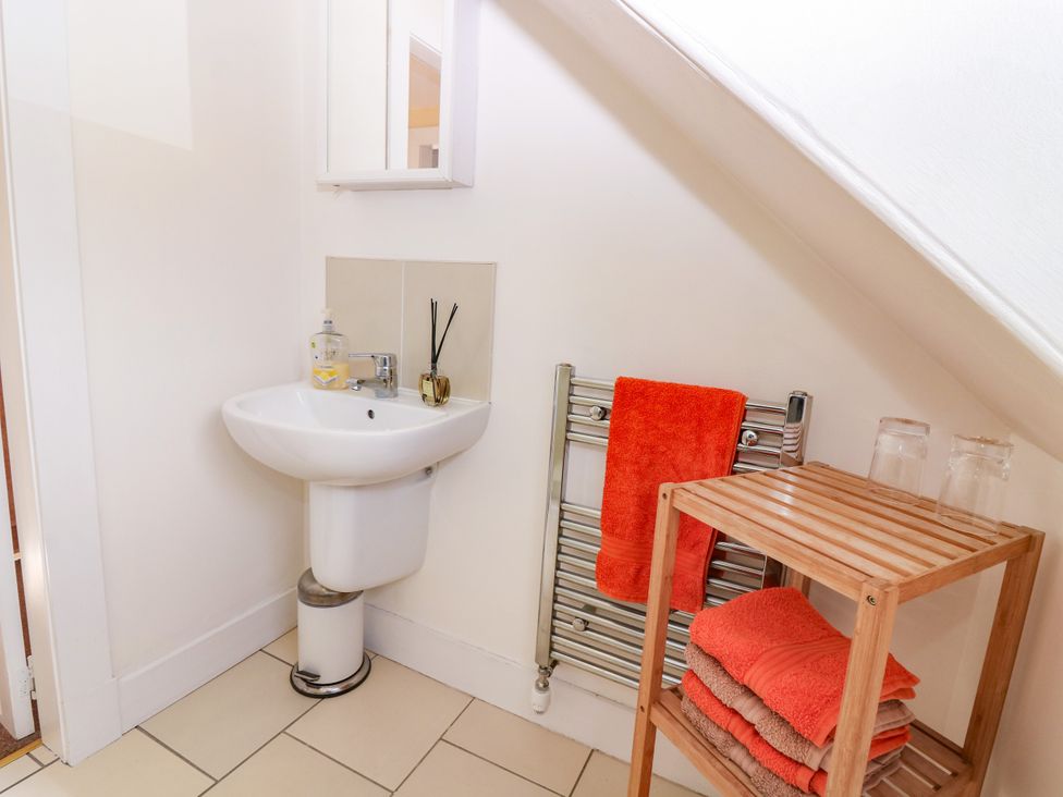 A bathroom with a sink, mirror, and towel storage at St Kilda in Ballater
