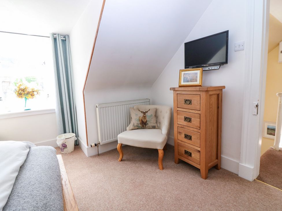 A bedroom with a chair and television at St Kilda in Ballater