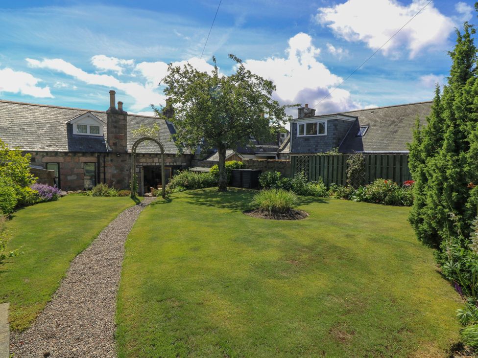 A garden with grass, a tree, and a path at St Kilda in Ballater